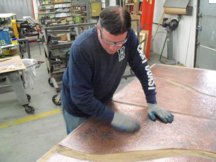 Buffing and polishing the copper to give it an aged and antiqued appearance.