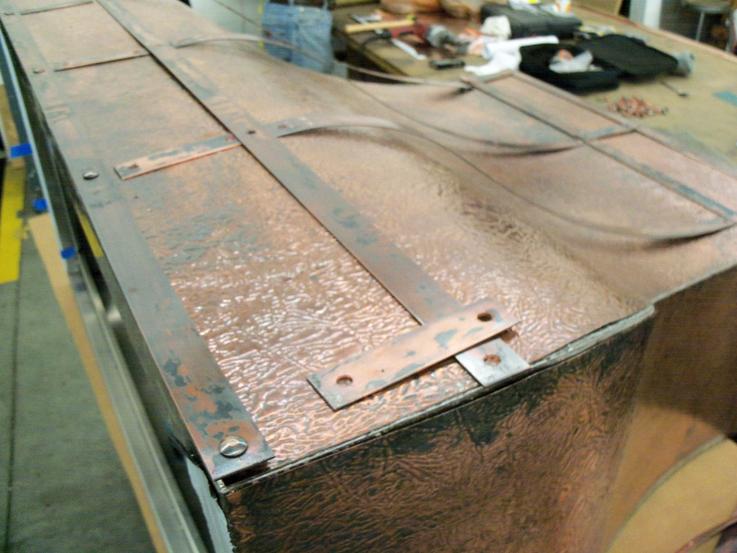 Preparing copper luggage straps to be attached to the body of the hood.